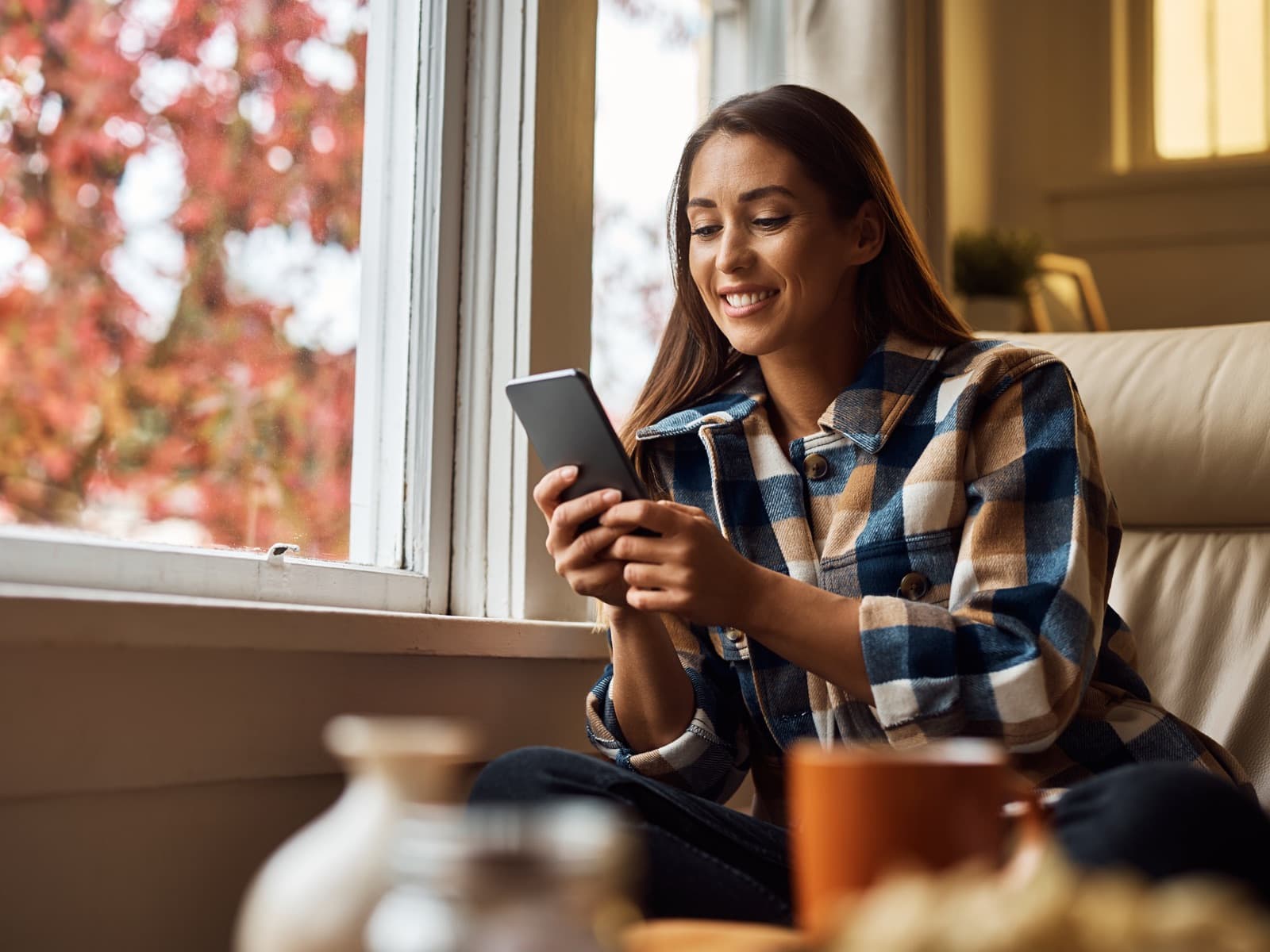 Woman smiling at phone on couch.